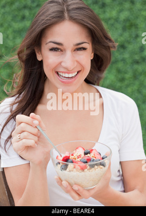 Donna ispanica mangiare cereali con frutta fresca Foto Stock