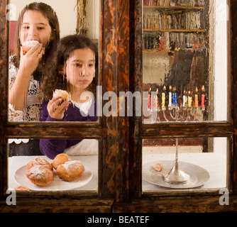 I bambini di fronte a un Hanukkia mangiare Jelly tradizionale ciambella in Hanukka Foto Stock