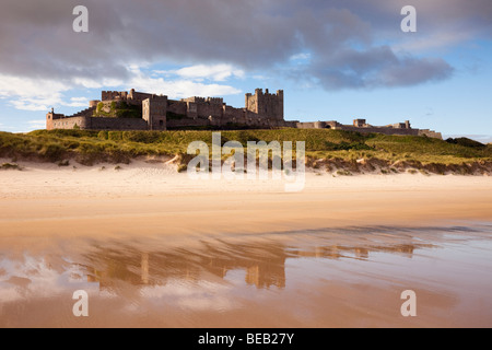 Il castello di Bamburgh riflessa nella sabbia bagnata sulla spiaggia vuota foreshore nel Northumbrian costa. Bamburgh, Northumberland, Inghilterra, Regno Unito, Gran Bretagna Foto Stock