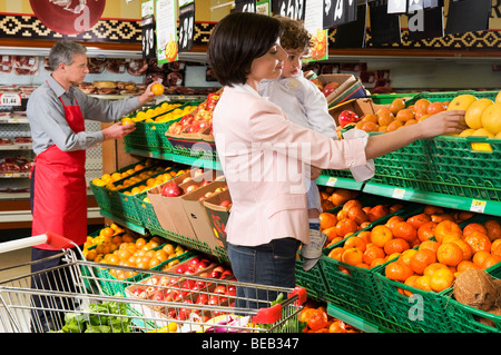 La donna che porta il suo figlio e acquisto di frutti in un supermercato Foto Stock