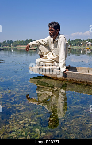 Uomo del Kashmir in appoggio sul suo Shikara (tradizionale barca). Manasbal Lago. Il Kashmir. India Foto Stock