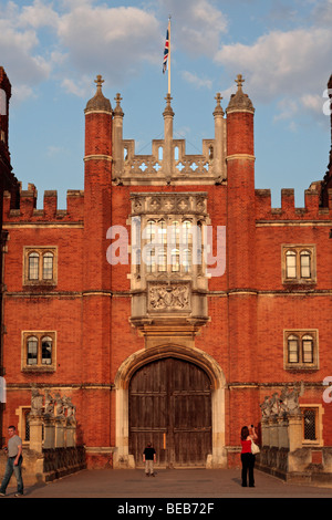 Un ragazzo giovane e i suoi genitori a cotta al sole entrata principale a Hampton Court Palace, Surrey, Regno Unito su una bella sera d'estate. Foto Stock