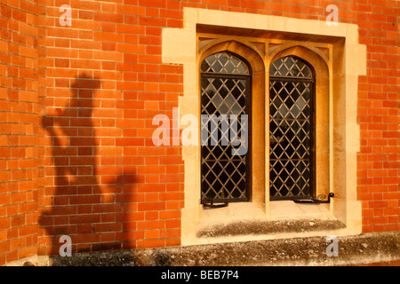 L ombra di una pianta ornamentale lion su sun lavato la parete accanto all'ingresso principale di Hampton Court Palace, Surrey, Regno Unito. Foto Stock