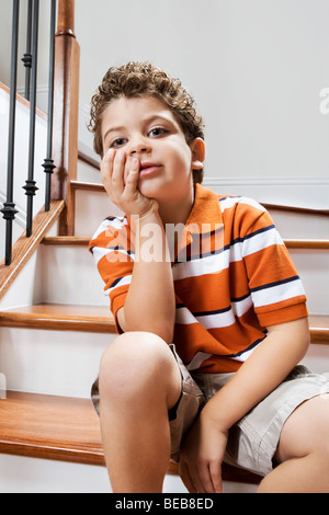 Ragazzo seduto su una scalinata e pensare Foto Stock