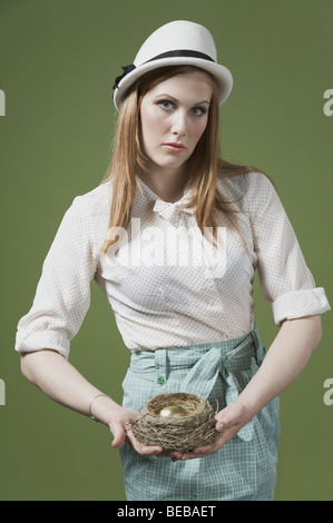 Ritratto di una donna tenendo un uovo dorato nel nido Foto Stock