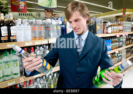 L'uomo comprare vodka bottiglie in un negozio di liquori Foto Stock