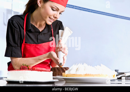 Lo chef femmina ciliegina di una torta Foto Stock