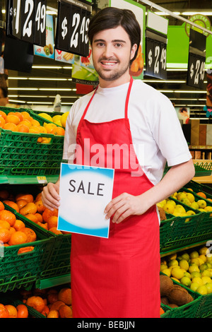 Venditore mostrando un cartello di vendita di fronte frutti" delle casse Foto Stock