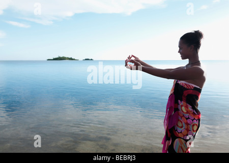 Donna stretching le sue braccia verso il mare Foto Stock