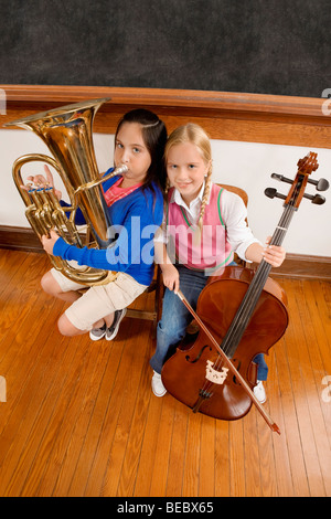 Due studentesse riproduzione di un violoncello e una tuba in una classe Foto Stock