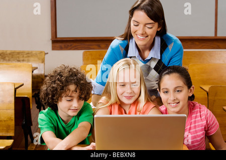 Gli studenti con il loro insegnante usando un computer portatile in un'aula Foto Stock