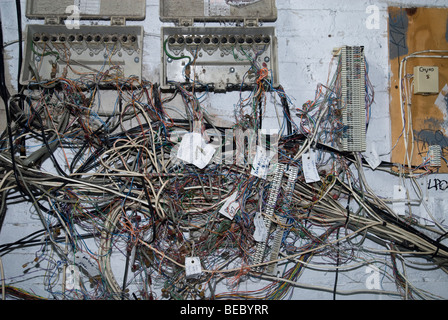 Un armadio di telefono mostra un rat's Nest di cavi e fili Foto Stock