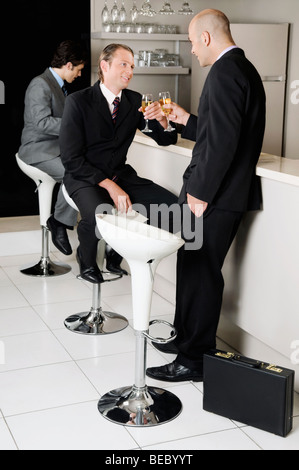 Due imprenditori tostare con il vino in un bar Foto Stock