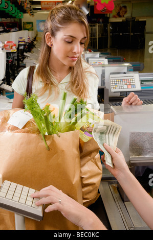 Addetto alle vendite il prelievo di denaro dal cliente presso la cassa Foto Stock