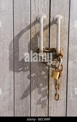 Rusty catena e un lucchetto su una coppia di capannone in legno maniglie in St Ives REGNO UNITO Foto Stock