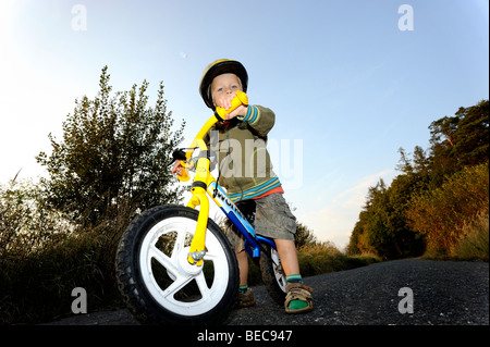 Bambino ragazzo in bicicletta attraverso una foresta corsa in bicicletta con il casco protettivo Foto Stock