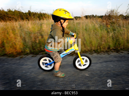 Bambino ragazzo in bicicletta attraverso una foresta corsa in bicicletta con il casco protettivo Foto Stock