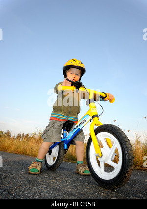 Bambino ragazzo in bicicletta attraverso una foresta corsa in bicicletta con il casco protettivo Foto Stock