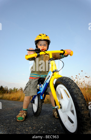 Bambino ragazzo in bicicletta attraverso una foresta corsa in bicicletta con il casco protettivo Foto Stock