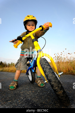 Bambino ragazzo in bicicletta attraverso una foresta corsa in bicicletta con il casco protettivo Foto Stock