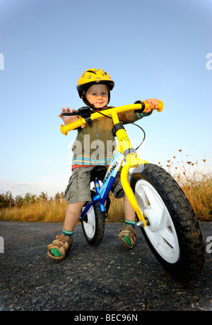 Bambino ragazzo in bicicletta attraverso una foresta corsa in bicicletta con il casco protettivo Foto Stock