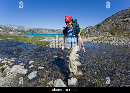 Giovane donna, escursionista con zaino, escursionismo, attraversando creek, bilanciamento sulle rocce, storico Chilkoot Pass, Chilkoot Trail, il Cratere La Foto Stock