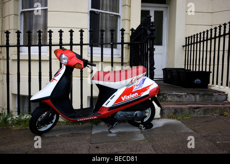 Vecchio vintage bianco e rosso Honda scooter Vision incatenato in strada per ringhiere in Hove, West Sussex, Regno Unito. Foto Stock