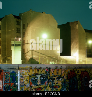 Con il muro di Berlino graffiti, torre di guardia e illuminato in terra di nessuno nel retro, Berlino, Germania Foto Stock
