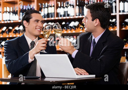 Due imprenditori tostare con il vino in un bar Foto Stock