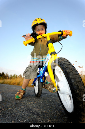 Bambino ragazzo in bicicletta attraverso una foresta corsa in bicicletta con il casco protettivo Foto Stock