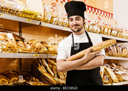 Venditore tenendo un filone di pane in un supermercato Foto Stock