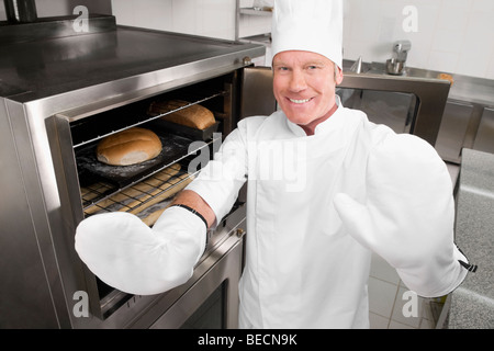 Chef in piedi in cucina e sorridente Foto Stock
