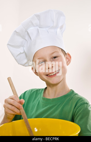 Ragazzo che indossa un chef hat agitazione in una ciotola Foto Stock