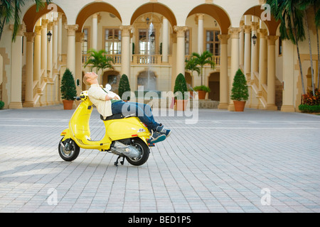 Uomo disteso su un ciclomotore di fronte ad un edificio, Biltmore Hotel Coral Gables, Florida, Stati Uniti d'America Foto Stock