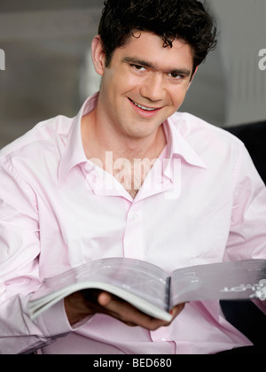 Ritratto di un giovane uomo con una rivista e sorridente Foto Stock