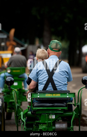 Un agricoltore e il suo nipote ride in una sfilata su un vintage trattore John Deere presso la contea di Whatcom macchinari antichi Show. Foto Stock