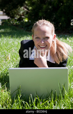 Felice giovane donna che lavorano su laptop all'aperto Foto Stock