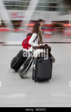 Immagine sfocata, giovane coppia rapidamente a piedi con i bagagli nella sala partenze presso l'aeroporto di Dusseldorf, Duesseldorf Nord Reno Foto Stock