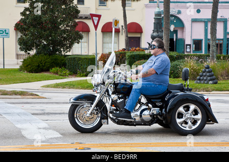 Uomo in sovrappeso che guida una motocicletta a tre ruote attraverso il centro di St Augustine, Florida, USA Foto Stock