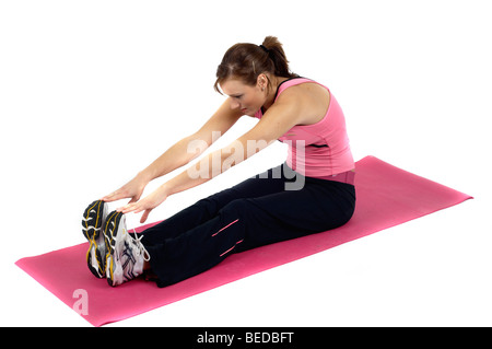 Giovane donna stretching su una stuoia Foto Stock