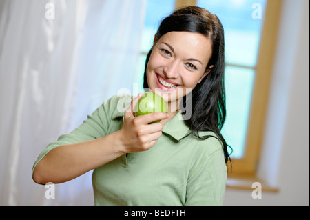 Donna prendendo un grande morso da una mela verde e sana alimentazione Foto Stock