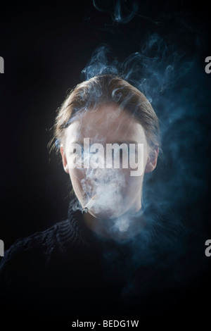 Ritratto di una giovane donna di fumare una sigaretta, fumo Foto Stock