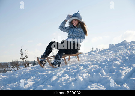 Giovane donna su una slitta nella neve Foto Stock