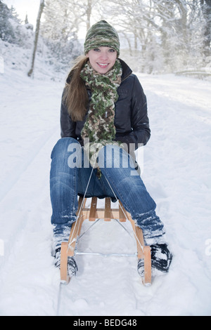 Giovane donna su una slitta nella neve Foto Stock