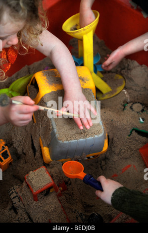 Bambini che giocano con i giocattoli in una buca di sabbia ad una scuola domenicale di Regno Unito Foto Stock