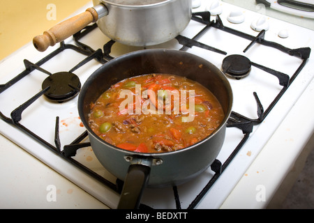 Pomodori, olive, peperoni e carni bovine simmering su un piano di cottura Foto Stock