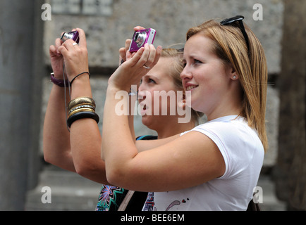 Due giovani donne bionda ragazze scattare una fotografia del Duomo di Milano dalla giunzione di Piazza del Duomo e Corso Vittorio Emanuele Foto Stock