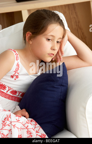 Ragazza giovane seduto sul divano di casa Foto Stock