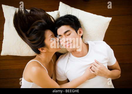 Asian Coppia giovane sdraiato sul pavimento kissing Foto Stock