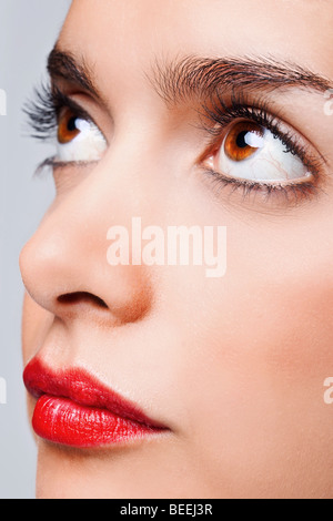 Close up volto ritratto di una donna con grandi occhi marroni e rosso brillante labbra Foto Stock